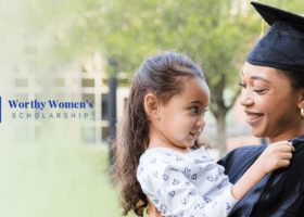A woman in a graduation cap and gown holding her daughter. Caption reads 2023 Worthy Women's Scholarship.